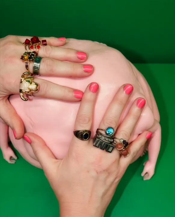 Hands with rings pressing into a pink lump